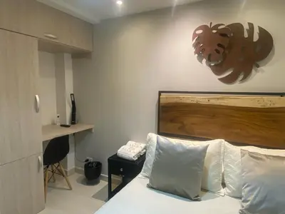 a bedroom with a bed with a wooden headboard and a desk at Maidy Luxury Hotel in Medellín