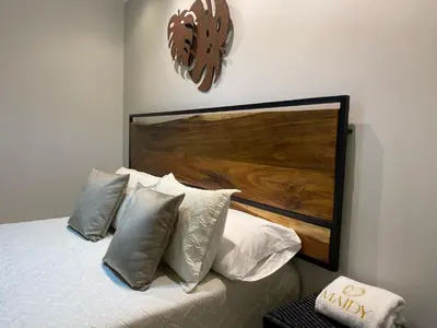 a bedroom with a bed with pillows and a wooden headboard at Maidy Luxury Hotel in Medellín