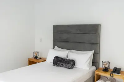 a bed with a black and white pillow on it at Hotel Nova El Peñol in El Peñol