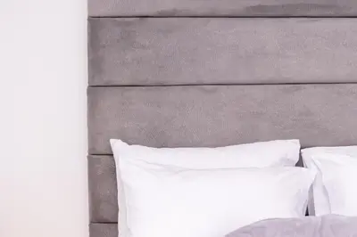 a bed with white pillows and a gray headboard at Hotel Nova El Peñol in El Peñol