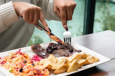 a person cutting a plate of food with a fork and knife at Hotel Nova El Peñol in El Peñol