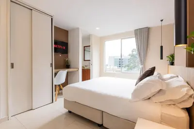 a bedroom with a white bed and a window at Central, Fast WiFi, AC and Poblado Views in Medellín