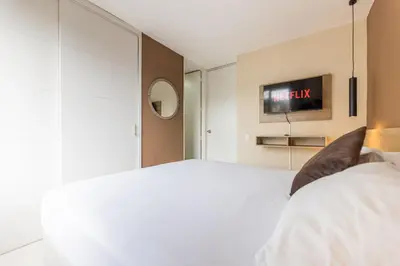 a bedroom with a bed and a tv on the wall at Central, Fast WiFi, AC and Poblado Views in Medellín