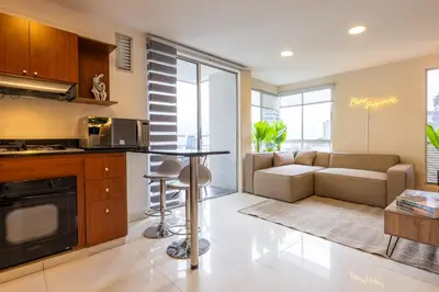 a kitchen and living room with a table and a couch at Central, Fast WiFi, AC and Poblado Views in Medellín