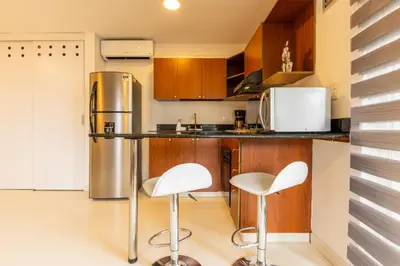 a kitchen with two white chairs and a refrigerator at Central, Fast WiFi, AC and Poblado Views in Medellín