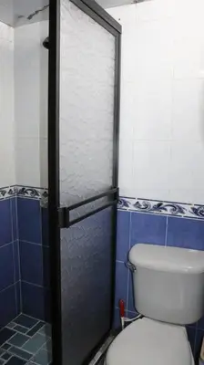 a bathroom with a toilet and a glass shower door at Hermosa casita cerca al centro in Medellín