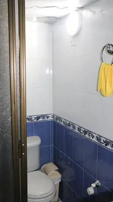 a bathroom with a toilet and a blue tiled wall at Hermosa casita cerca al centro in Medellín