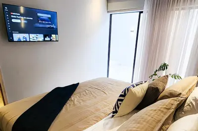 a bedroom with a bed with a tv on the wall at Las Lomas Luxury House2 in Medellín