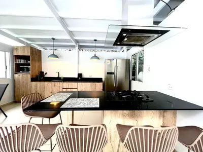 a kitchen with a black counter top and chairs at Luxury Villa In Aguacatala2 in Medellín