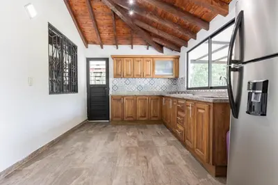 a kitchen with wooden cabinets and a refrigerator at Finca Turística Peñoles - Cerca de Charcos y Cascadas - Finca Rústica en San Carlos, Antioquia in San Carlos