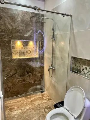 a bathroom with a toilet and a glass shower at HOTEL TORRE DELUXE ¨SANTORINI¨ in Doradal