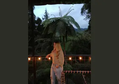 a woman standing in front of a palm tree at Hotel Cabañas y Chalets lujosos Mágica Luna Manizales in Villamaría