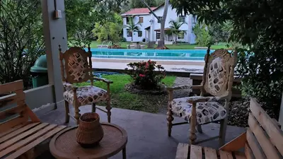 a porch with two chairs and a table and a house at CASA HOTEL FIBA MAGUEZA in Guarne