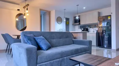 a living room with a blue couch and a kitchen at Stunning, Brand-new Apartment in Santa Fe de Antioquia