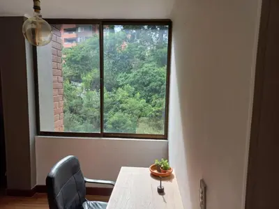 a table and chair in front of a large window at Poblado la 10 in Medellín