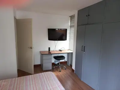 a bedroom with a desk with a computer and a tv at Poblado la 10 in Medellín