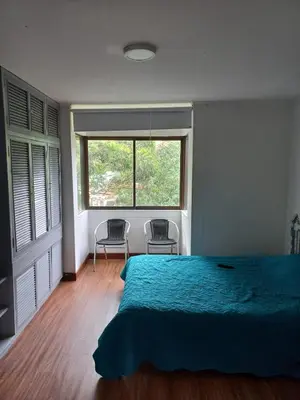 a bedroom with a bed and two chairs and a window at Poblado la 10 in Medellín