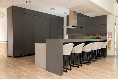 a kitchen with black cabinets and white stools at Espectacular Villa en Copacabana in Copacabana