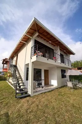 a small white house with a porch and a balcony at Monte Hermoso - Apartamento campestre in Guatapé
