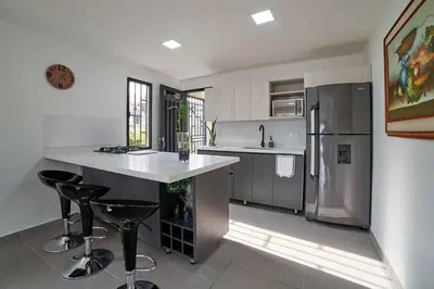 a kitchen with a stainless steel refrigerator and bar stools at Monte Hermoso - Apartamento campestre in Guatapé