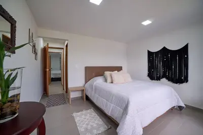 a white bedroom with a bed and a mirror at Monte Hermoso - Apartamento campestre in Guatapé