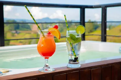 two cocktails sitting on a table with a view at Glamping en Guatape Wifi Jacuzzi in Guatapé