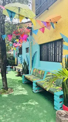 a bench sitting outside of a building with an umbrella at Baku Laureles Hostel in Medellín