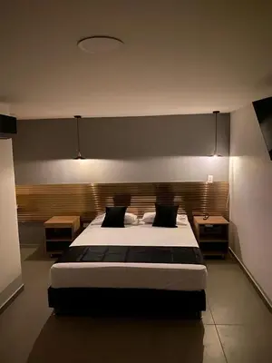 a bedroom with a large bed and two tables at HOTEL ESTADIO DORADO in Medellín