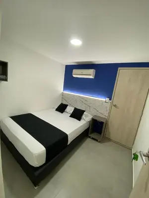 a bedroom with a bed with a blue wall at HOTEL ESTADIO DORADO in Medellín