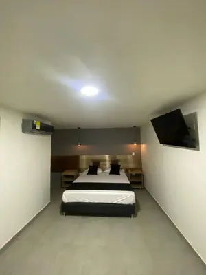 a bedroom with a bed and a flat screen tv at HOTEL ESTADIO DORADO in Medellín