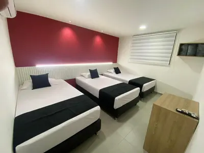 a room with three beds and a red wall at HOTEL ESTADIO DORADO in Medellín