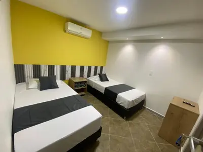 a bedroom with two beds and a yellow wall at HOTEL ESTADIO DORADO in Medellín