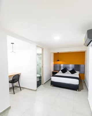 a bedroom with a bed and a desk and a chair at HOTEL ESTADIO DORADO in Medellín