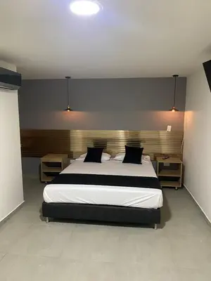 a bedroom with a large bed with black and white sheets at HOTEL ESTADIO DORADO in Medellín