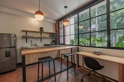 a kitchen with two stools and a counter and some windows at The Somos Flats Laureles in Medellín