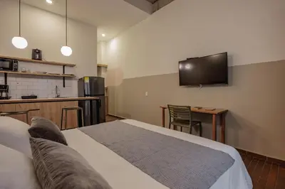 a room with a bed and a tv on the wall at The Somos Flats Laureles in Medellín
