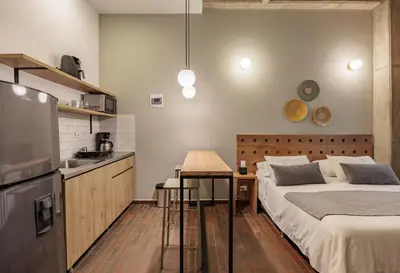 a bedroom with a bed and a table and a kitchen at The Somos Flats Laureles in Medellín