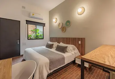 a bedroom with a bed and a table and a window at The Somos Flats Laureles in Medellín