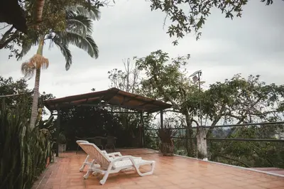 a patio with two white chairs and a umbrella at APARTAMENTO CAMPESTRE EN EJE CAFETERO in Manizales