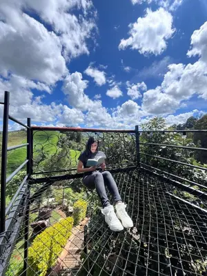 a woman sitting on top of a cage with a book at Glamping Milagros in San Pedro