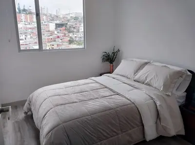 a bed in a white room with a window at Confortable apartamento in Manizales