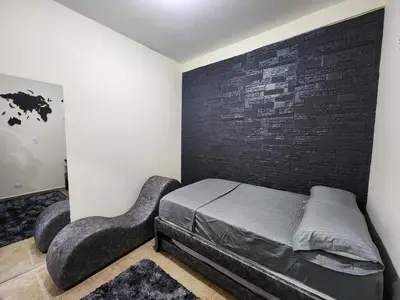 a bedroom with a bed and a black brick wall at Alojamiento con Aire acondicionado - Shelter La Perla in San Luis