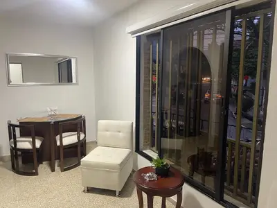 a living room with a table and a chair and a window at Apartamento en laureles con excelente ubicación in Medellín