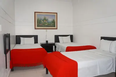 a room with two beds with red and white sheets at Hotel Las Rampas in Medellín