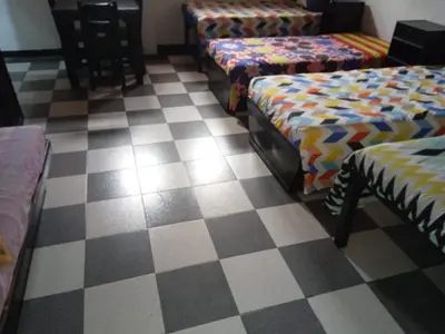 a room with three beds and a checkered floor at Hotel Las Rampas in Medellín