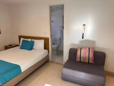 a bedroom with a bed and a chair in it at Amoblados Medellín Laureles in Medellín