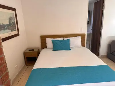 a bedroom with a bed with a blue pillow on it at Amoblados Medellín Laureles in Medellín