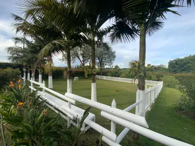 a white fence with palm trees and a field at Finca Hotel 12 Palmas- Aeropuerto JMC in Rionegro