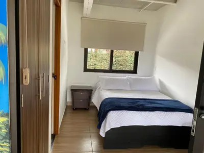 a small bedroom with a bed and a window at Finca Hotel 12 Palmas- Aeropuerto JMC in Rionegro