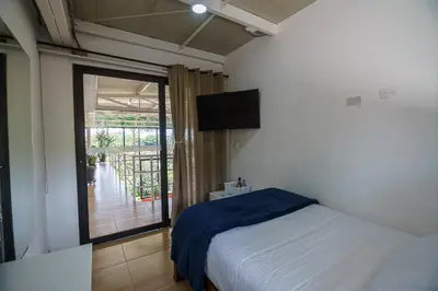a bedroom with a bed and a balcony with a television at Finca Hotel 12 Palmas- Aeropuerto JMC in Rionegro